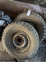 Two Suburbanite H78-15 tires on rusty six-lug steel rims stacked on floor