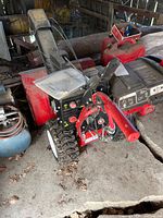 Overall view of Troy-Bilt three-stage snow thrower showing auger housing, control panel, handlebars and tires