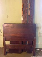 Headboard, footboard, side rails, support slat visible leaning against wall