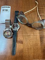 Entire lot: two wristwatches and vintage goggles on tabletop