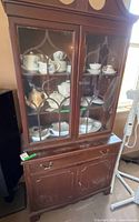 Full frontal view of china cabinet showing glass doors, lower drawer and cupboard