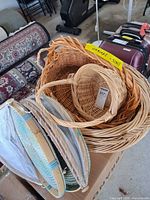 Assorted wicker baskets stacked together with two bamboo trays having white mesh covers