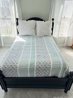 Bed made with quilt, pillows and sheets visible