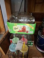 Cases of Ball quart mason jars stacked with four handled mason jar mugs in wire rack