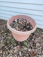 One of the three terracotta-colored plastic planters outdoors, shows size, color, weathering and cracks