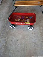 Full view of red Radio Flyer wagon on floor showing wheels and stickered interior