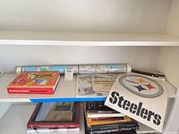 Shelf with Howard Stern book, rolled map, Steelers decal, additional books