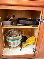 Cabinet view showing colander, mesh strainers, spoon and funnel