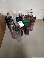 Group shot of all 15 assorted travel cups and bottles on floor
