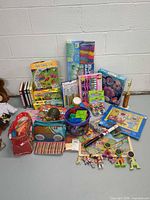 Group shot of all unopened toys, books, craft kits and accessories arranged against wall