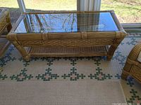 Full view of rectangular wicker coffee table with glass top and lower shelf