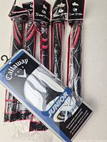 Five packaged SuperStroke Cross Comfort Slim 3.0 midsize grips alongside packaged Callaway Junior X Series glove