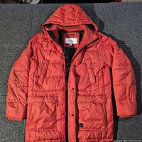 Front view of orange Calvin Klein hooded puffer jacket showing zipper, pockets, hood
