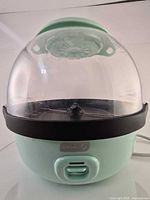 Front view of assembled Dash popcorn maker showing clear dome and aqua base