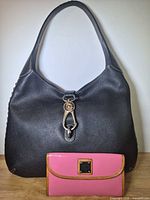 Front view of black leather handbag and pink wallet