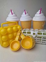 Overall lot showing three cups, freezer mold, measuring cups, and dishwasher basket