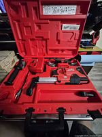 Entire kit inside red Milwaukee case showing tool, charger, handle and clamps