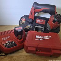 All items grouped: band saw, charger, battery, red hole saw kit case