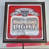 Front view of illuminated Budweiser Light sign with frame and cord visible