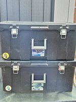 Two stacked black Sterilite footlockers showing front latches and handles