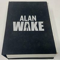 Front of black hard cover collector’s case showing Alan Wake logo