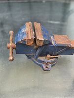 Side view of blue bench vise showing jaws, handle and rust