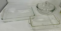 Three clear glass baking dishes: two square, one round with lid