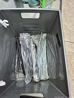 Tote containing sealed bags of black and silver metal pegs