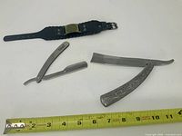Overall view of bracelet and two razors with ruler for scale