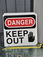 Front of square metal sign showing text and hand symbol