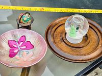 All four items grouped: globe on stand, ceramic butterfly plate, wooden plate, snow globe