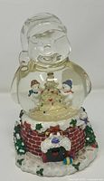 Front view of snowman water globe showing internal Christmas scene and brick fireplace base