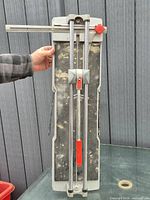 Front view of tile cutter showing rails, handle, knob and bed