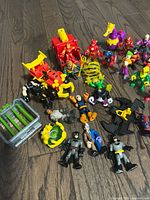 Overview of assorted Imaginext mini figures, cage trap and accessories on wood floor