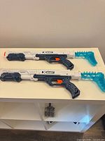 Two white/navy X-Shot blasters on shelf
