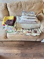 Full lot on couch showing quilts, sheets, towel stack