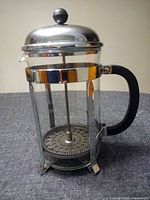 Side view of Bodum French press showing glass carafe, stainless frame, black handle, lid and plunger