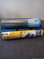 Broadstone tent in blue carry bag beneath Makobe sleeping pad in plastic wrap