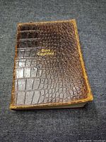 Front cover showing brown crocodile-pattern leather and gilt title