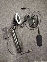 All three items laid out: microphone with base, selfie stick collapsed, USB hub