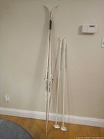 Full view of skis and poles leaning against wall