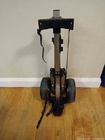 Cart folded upright showing aluminum frame and two wheels