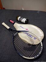 Two rackets, cream racket cover, wine bottle visible