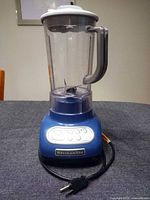 Front view of assembled blue KitchenAid blender showing control panel and plug