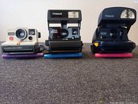 Front view of three Polaroid cameras aligned on table