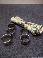 Six engraved silver plated napkin rings with napkin for scale
