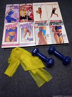 All eight VHS tapes, dumbbells, resistance band displayed