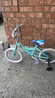 Left side view of complete Frozen themed children’s bike against brick wall