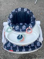 Front view of assembled floor seat showing fabric insert, tray and toys