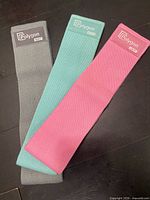 Three resistance bands laid flat showing colors and Polygon branding